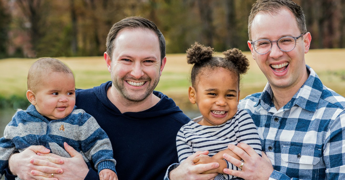 Capital One associate Ethan sits in a field with his husband and their two kids and talks about the adoption benefits Capital One provides to same-sex couples